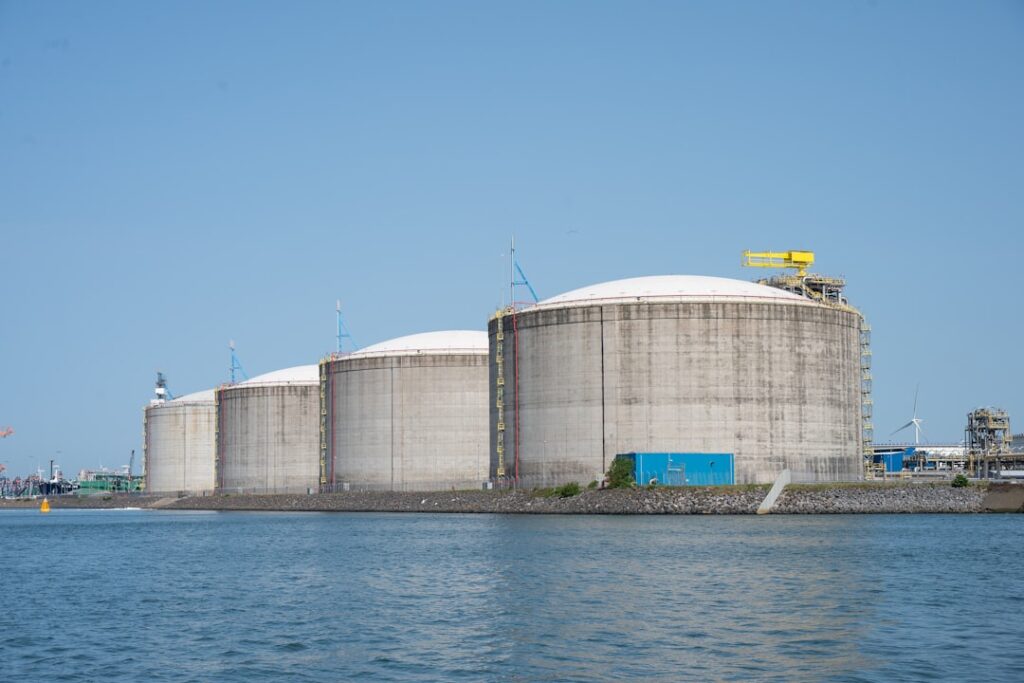 A concrete berm and lined pit surrounding a large outdoor chemical storage tank.